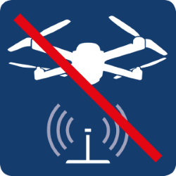 Piktogramm „Drohnenflug verboten“ mit durchgestrichener Drohne über einem ebenfalls durchgestrichenen Funkturm.