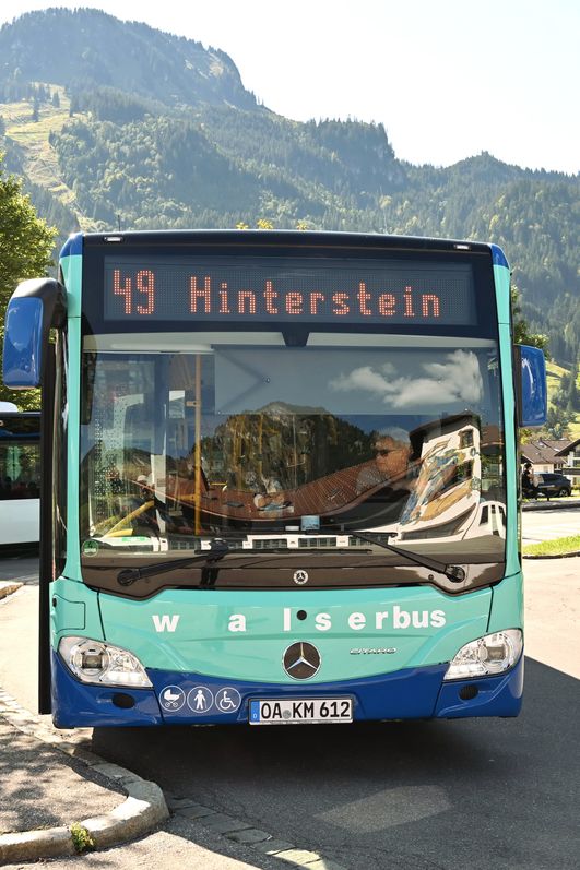 Blauer Walserbus am Busbahnhof Bad Hindelang mit Ziel Hinterstein (Linie 49) und Bergen im Hintergrund.