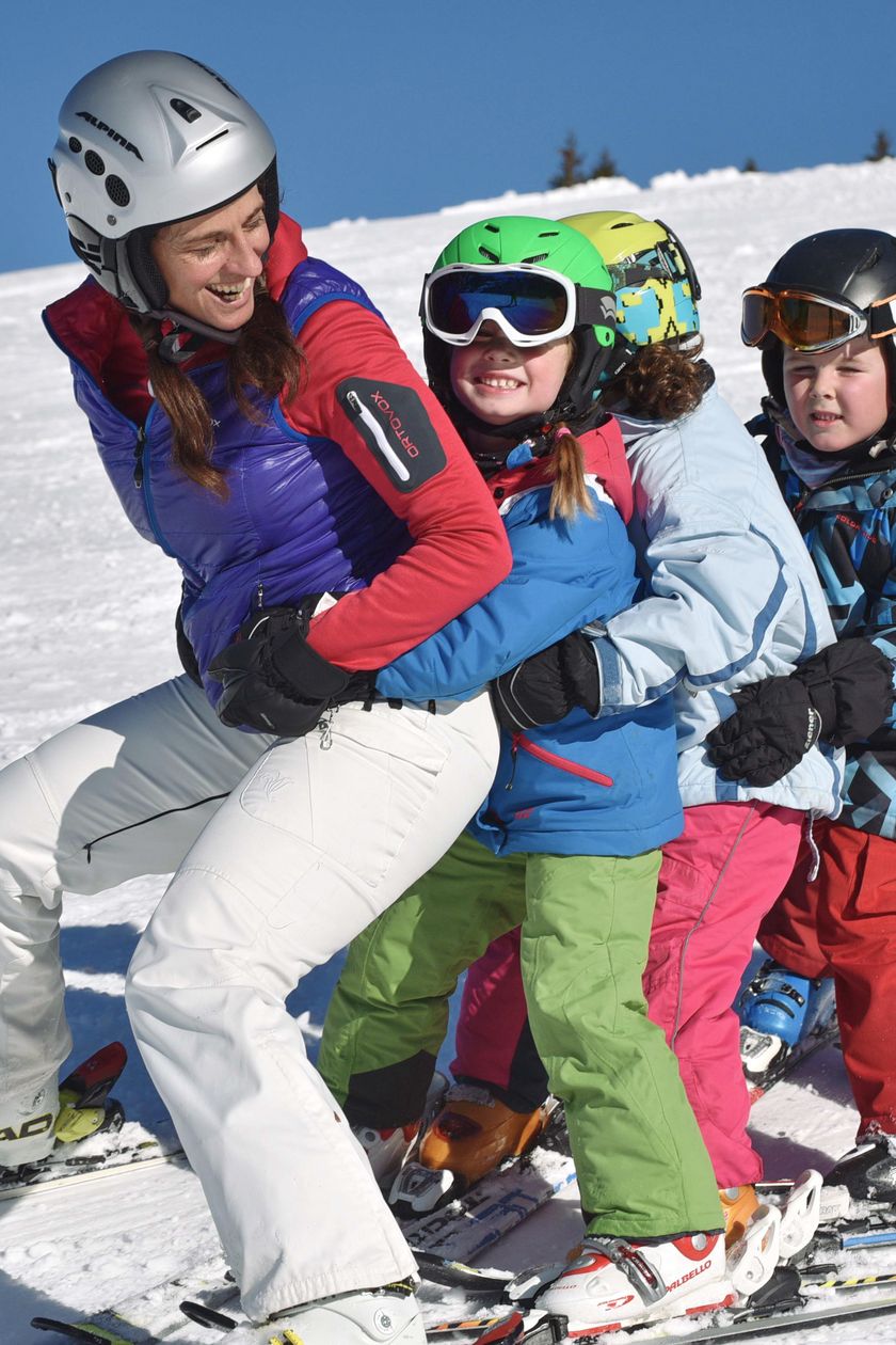 Eine Skilehrerin und fünf Skikurs-Kinder stehen in einer Reihe auf einer Piste.