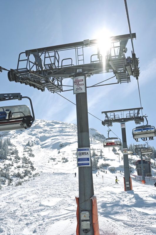 Ein Sessellift befördert Wintersportler zum Skifahren in Oberjoch den verschneiten Hang hinauf in Richtung Gipfel.