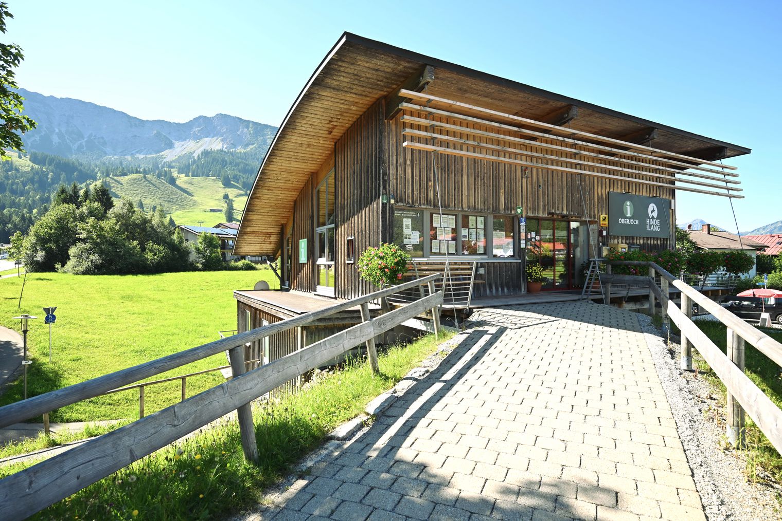 Touristische Informationszentrum Bad Hindelang Oberjoch im Allgäu mit modernem Holzbau und barrierefreiem Zugang bei Sonnenschein.